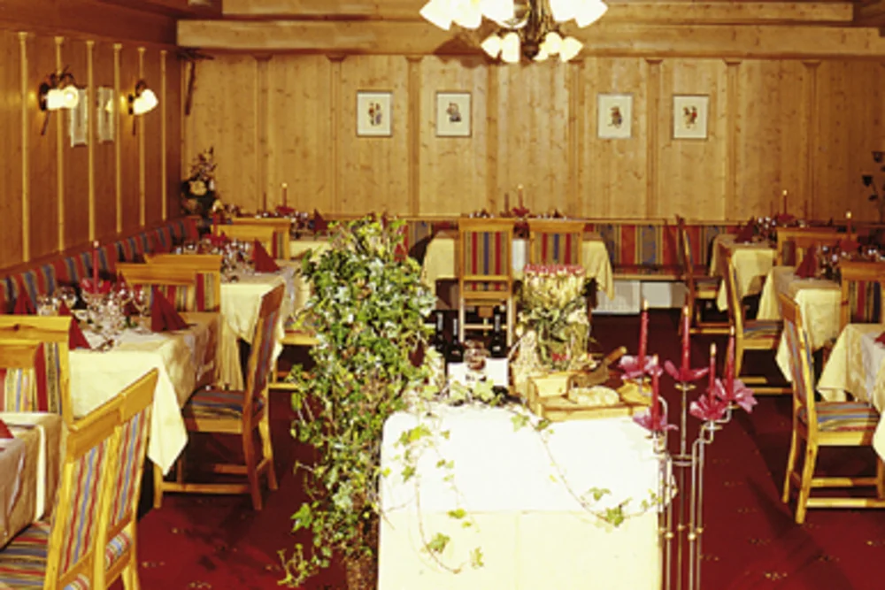 The festively furnished dining room of the Alphotel Tyrol, with warm wood tones and red carpet, invites special occasions.